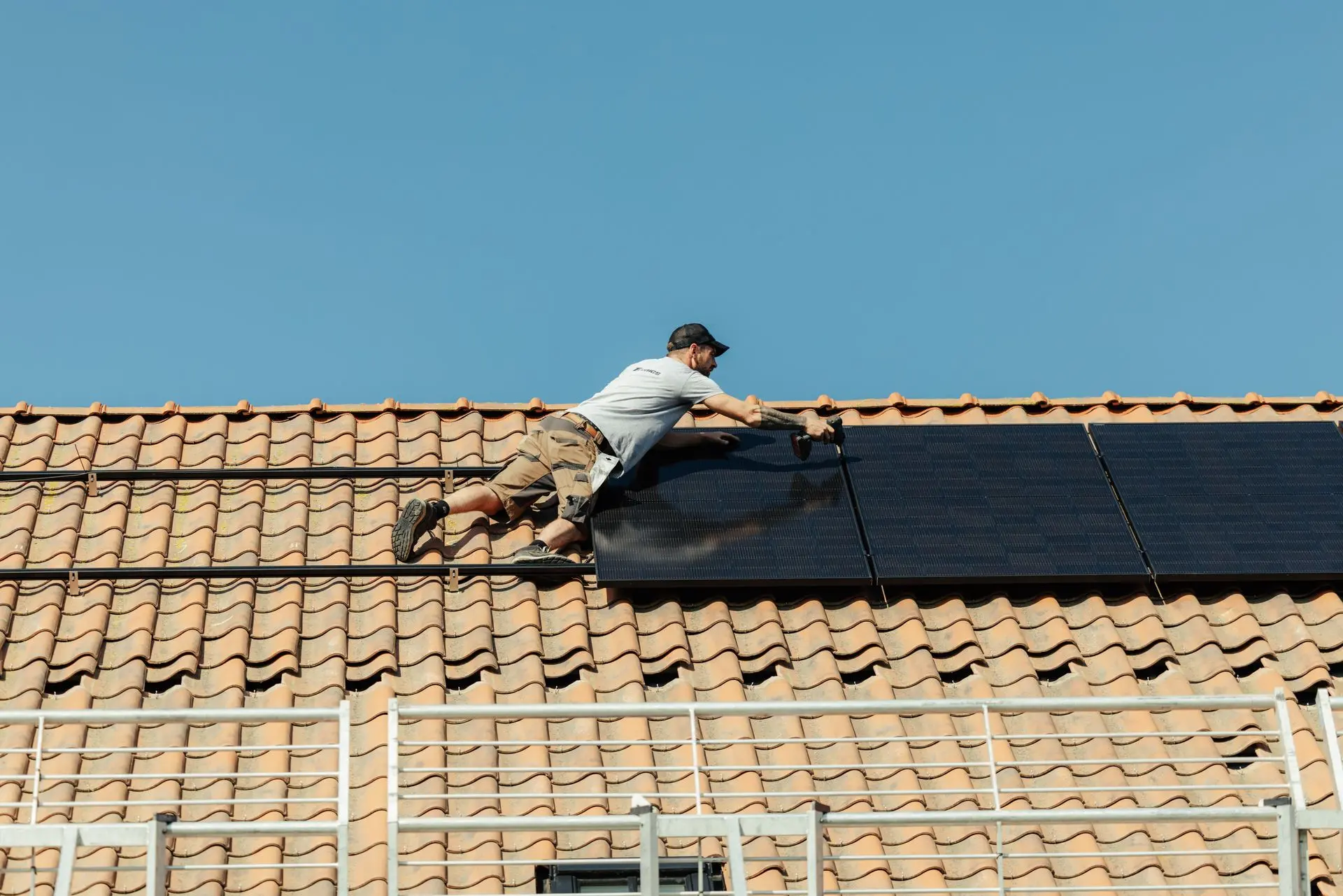 Installateur monteert zonnepanelen op schuin dak van woning