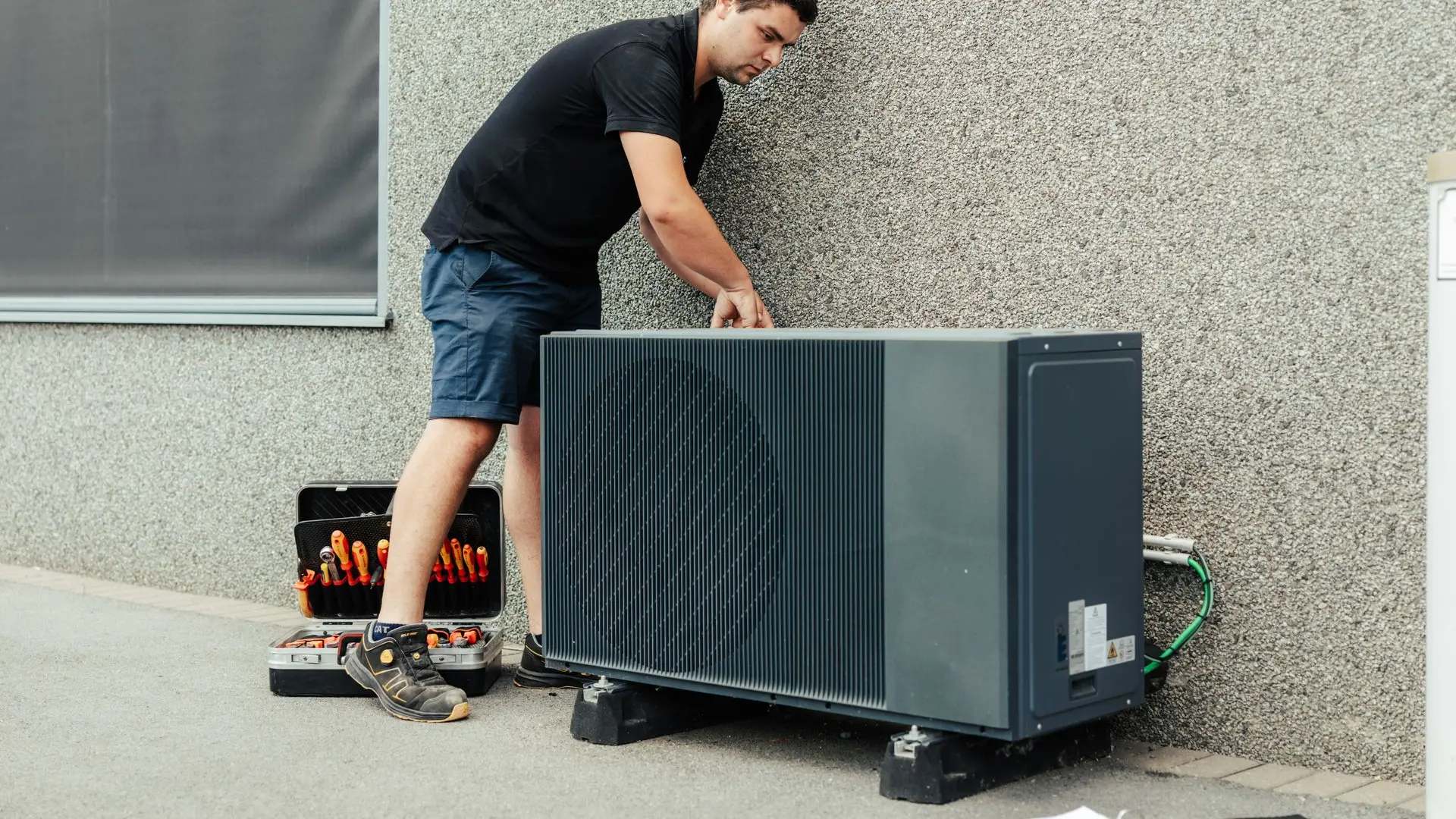 installateurs plaatst buitenunit voor warmtepomp woning